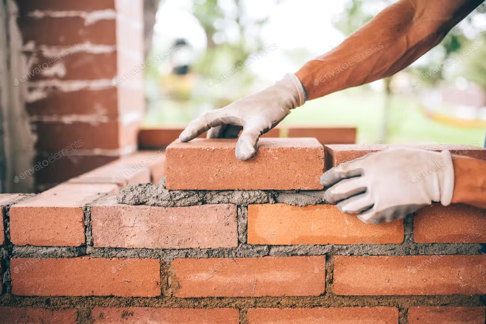 Bricklayer installing bricks with mortar mix in a masonry project