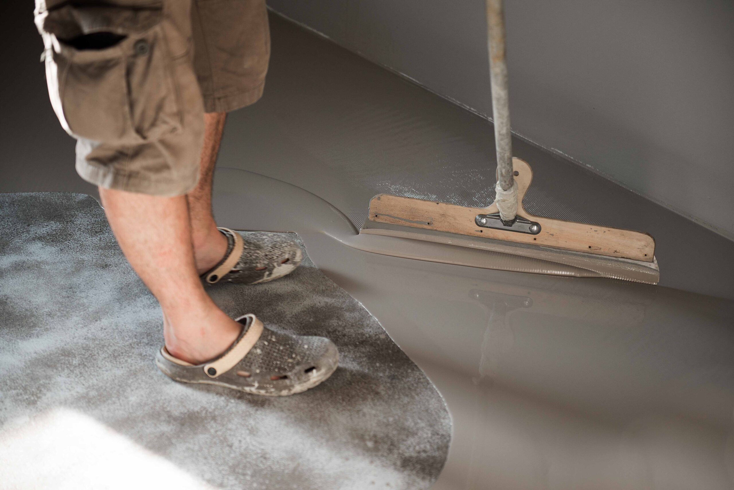 Photo of a man wearing Crocs sandals cleaning the floor.